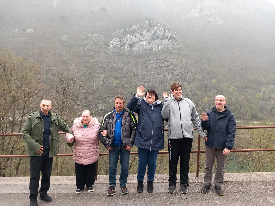 Skupina uporabnikov se fotografira ob cesti, v ozadju je hrib Sabotin