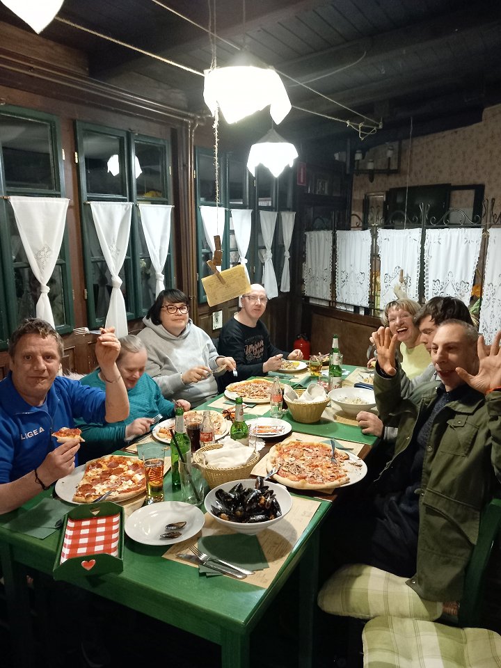 Skupina uporabnikov sedi za mizo v piceriji