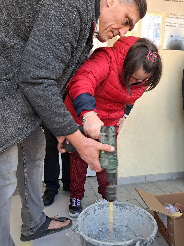 Uporabnica z mešalcem pripravlja lepilo za lepljenje ploščic na zid