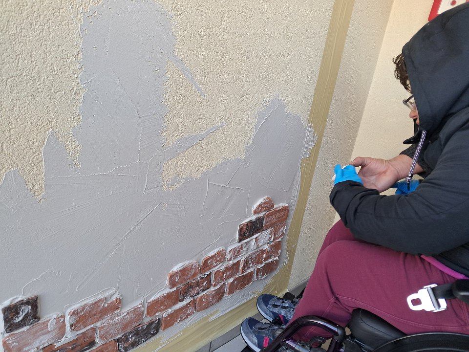 Uporabnica na vozičku lepi ploščice na zid